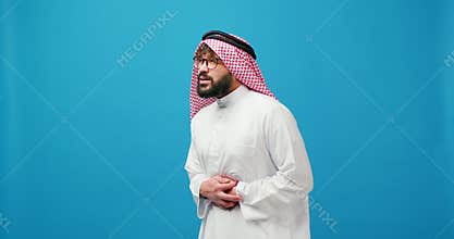 Sad, upset sick Muslim man wearing stylish keffiyeh having belly pain spasm isolated on blue background