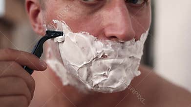 Man shaves precisely, Preparing for lessons with grooming, Carefully shaping beard edges for teaching session, Focused individual