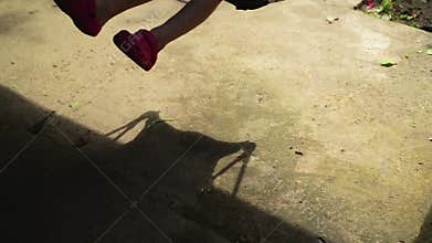 Shadow of unrecognizable boy child on a swing seat in summer afternoon.