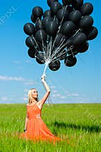 Woman looking up at the black balloons