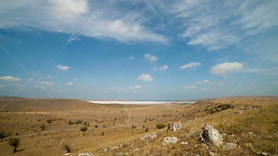 Clouds float over the fields and dry lake.