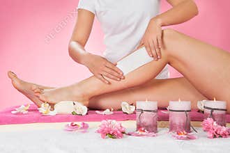 Therapist waxing customer's leg at spa