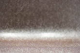 Sparkling surface reflects light in a bright setting creating a shiny display of small particles and textures in the background