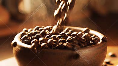 Coffee beans pouring into wooden bowl