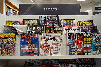 Sports magazines on bookstore shelf with basketball hockey football and baseball covers.