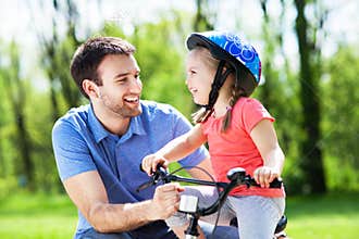 Girl learning to ride a bike with her father