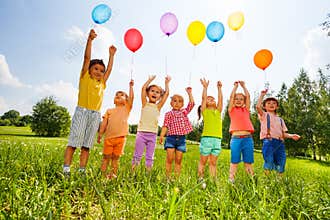 Happy kids with balloons and arms up in the sky