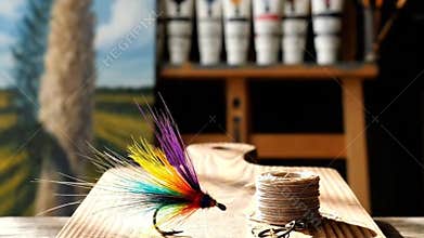Colorful Fishing Fly on Wooden Cutting Board With Paint Tubes And Landscape Painting in Backgrounds Still Life Setup In