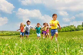Running kids in green field during summer