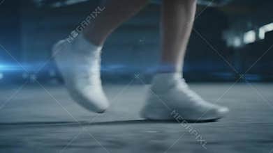 Legs in White Sneakers Stepping on Concrete in Motion Blur in Industrial Environment with Cool Blue Lighting Style Gym Training or
