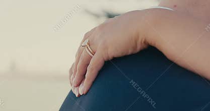 A close up of the bride hands gently embracing her groom as they look tenderly at each other, with a large diamond on the bride