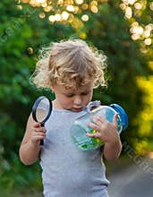 A child looks into a jar with a magnifying glass. Selective focus.