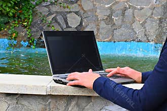Working on a laptop outdoors by a waterfall, Calm workspace in nature