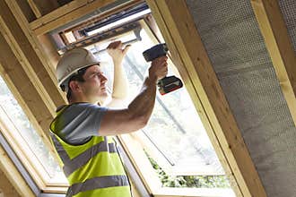 Construction Worker Using Drill To Install Window
