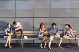 College students sitting on bench modern wall