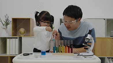toddler girl scientist study using pipette dropping liquid with test tube and beaker. learning science with father