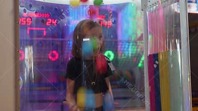 Shocked girl watching colorful ball fall at arcade game booth in shopping mall