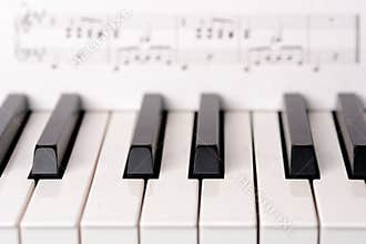 Close-up piano keyboard. Sheet music on background is copyright free