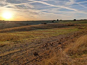 Sunset view over rolling hills and grassy fields in rural landscape during evening hours