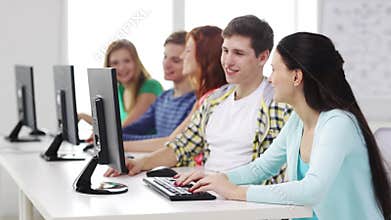 Smiling students working with computers at school