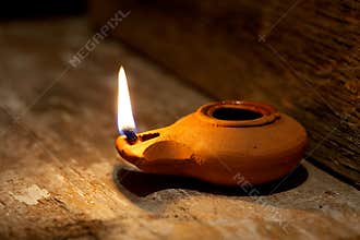 Ancient Middle Eastern oil lamp made in clay on wood table