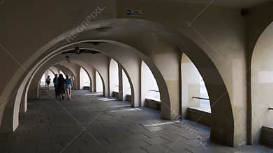 Long arched passageway with repeating arcades and people walking in the distance in Krakow
