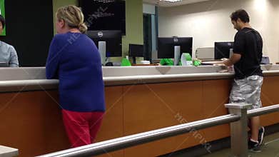 People at a service counter talking to the teller