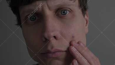 Man noticing single pimple on his face, examining skin in mirror, acne and blemish problem, realistic skincare and self care