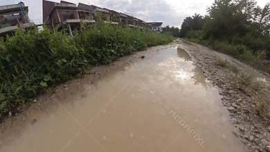 puddle along the diminishing perspective rural pathway into the rural countryside by the construction site.
