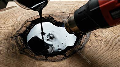 Epoxy resin filling a wood knot with a heat gun. Carpenter repairing a natural defect in a wooden surface.