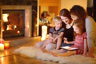 Happy family using a tablet pc by a fireplace
