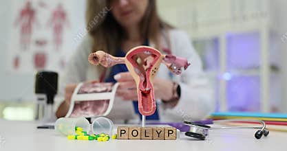 Wooden blocks spell word Polyp near uterus model on table