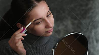 Girl Applies Makeup Concealer In Front Of Mirror