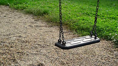 Empty swing seat swaying at playground in the park.