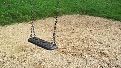 Empty swing seat swaying at playground in the park.
