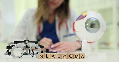 Wooden blocks spell word Glaucoma near eyeball model and lenses