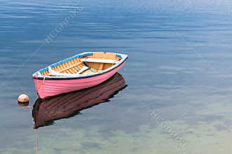 A single pink boat in clear blue water