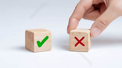 A hand placing a wooden block with a green check mark on it