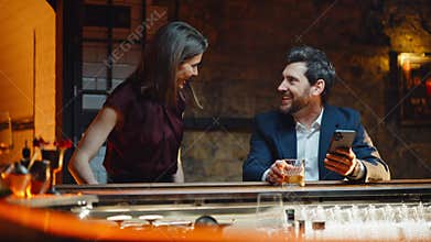 Man using mobile alone sipping brandy in bar closeup. Surprised couple meeting