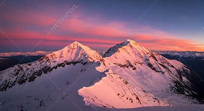 Two snow covered mountain peaks at sunrise with pink sky image