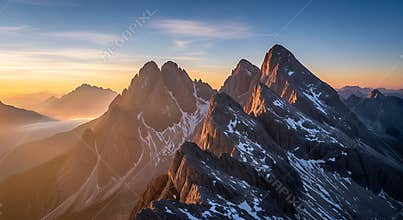 Jagged mountain peaks bathed in golden sunrise light with snow patches rock