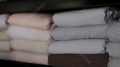 Organized textile shop displaying neatly rolled fabrics in variety of colours and textures. Shelves are stocked with