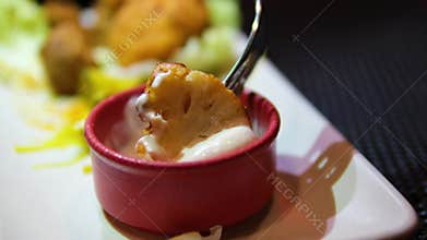 Close-up of frying pan with pieces of cauliflower in batter of beaten eggs frying on it. Deep-fried cauliflower is fried