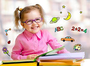 Happy child girl in glasses reading books in library