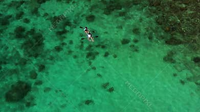 A couple of tourists kayak along the coral reef on Redang Island in Malaysia
