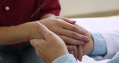Close up view of doctor gently holding female patient hands