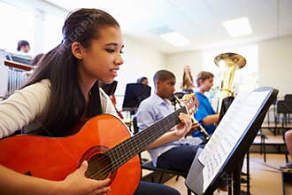 Female Pupil Playing Guitar In High School Orchestra