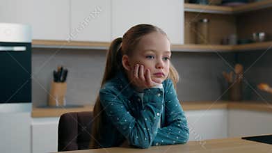 Sad upset pensive thoughtful little offended Caucasian child girl orphan unhappy bad mood lonely kid at home kitchen