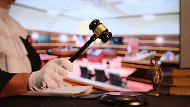 Courtroom with focus on gavel, law books and justice statue.