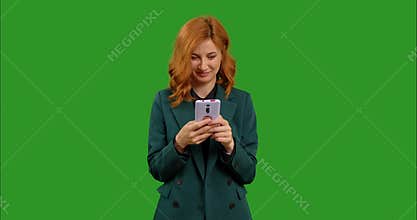 Female reading text message on her mobile phone over green screen background chroma Key.